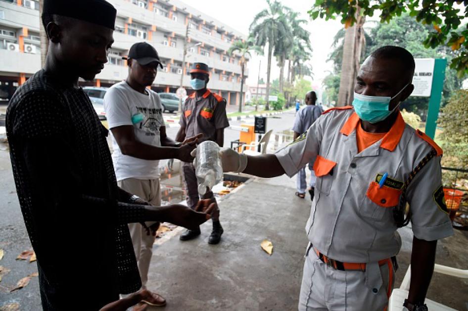 Un membre du personnel de sécurité d'un hôpital public à Lagos, au Nigeria, verse du liquide désinfectant dans la main d’un visiteur, le 28 février 2020.