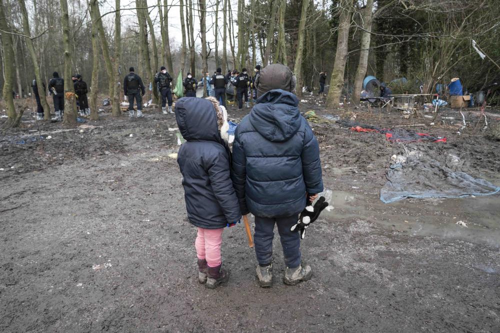 Deux enfants regardent la police saisir leur tente durant l’expulsion d’un campement à Grande-Synthe, dans le nord de la France, le 21 janvier 2021.