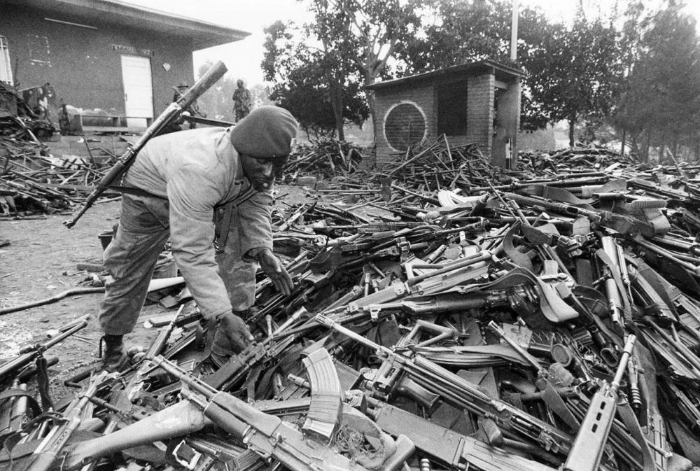 A Zairian soldier with a pile of weapons left by Rwandan soldiers and militiamen who had fled Rwanda to Congo (then Zaire), to escape the RPF advance.