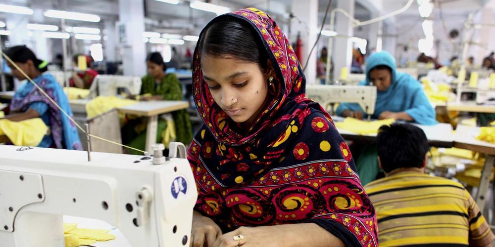 Une ouvrière du textile coud des vêtements dans un bâtiment à proximité du site de l'effondrement de l’immeuble du Rana Plaza, dans la banlieue de Dhaka, au Bangladesh