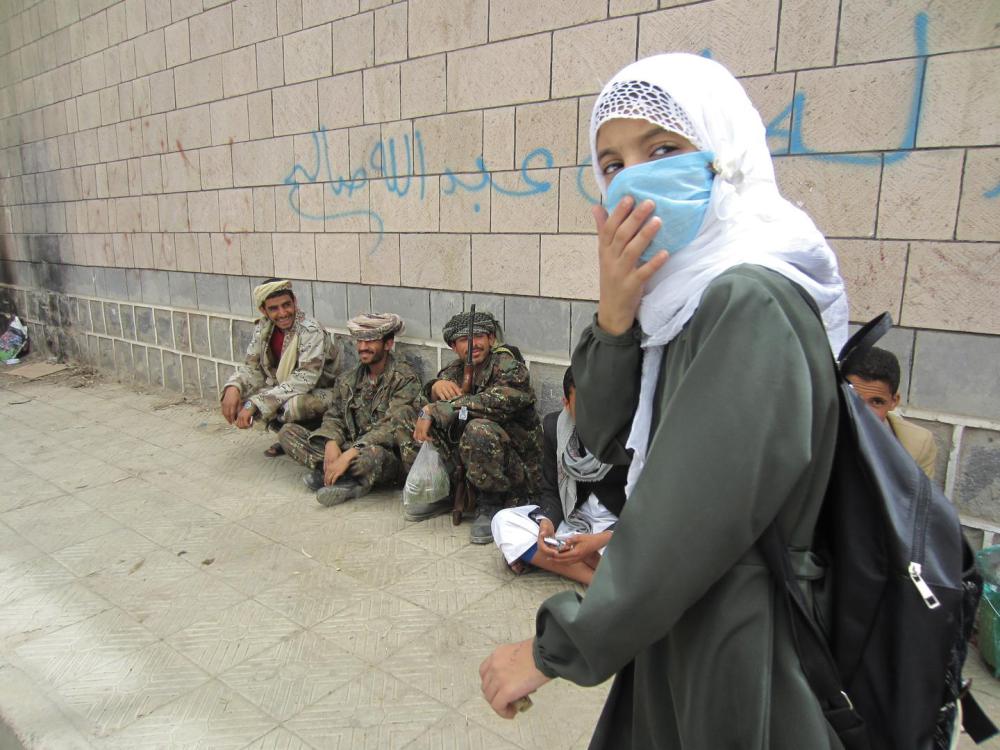 Une étudiante quitte l’école al-Furadh en fin de journée. Les soldats se détendent et mâchent du khat à l'extérieur de l'enceinte de l'école. Ils ont vécu dans les classes du troisième étage pendant plusieurs mois, ont indiqué les élèves et enseignants. 