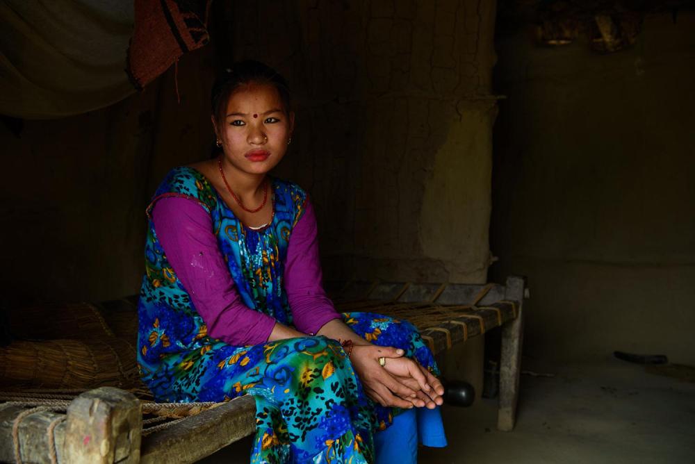 Ganga M., 17, sits inside her home in Kailali, Nepal. Ganga had an arranged marriage at the age of 16 and was five months pregnant when this photograph was taken. Her husband works as a cook in India.