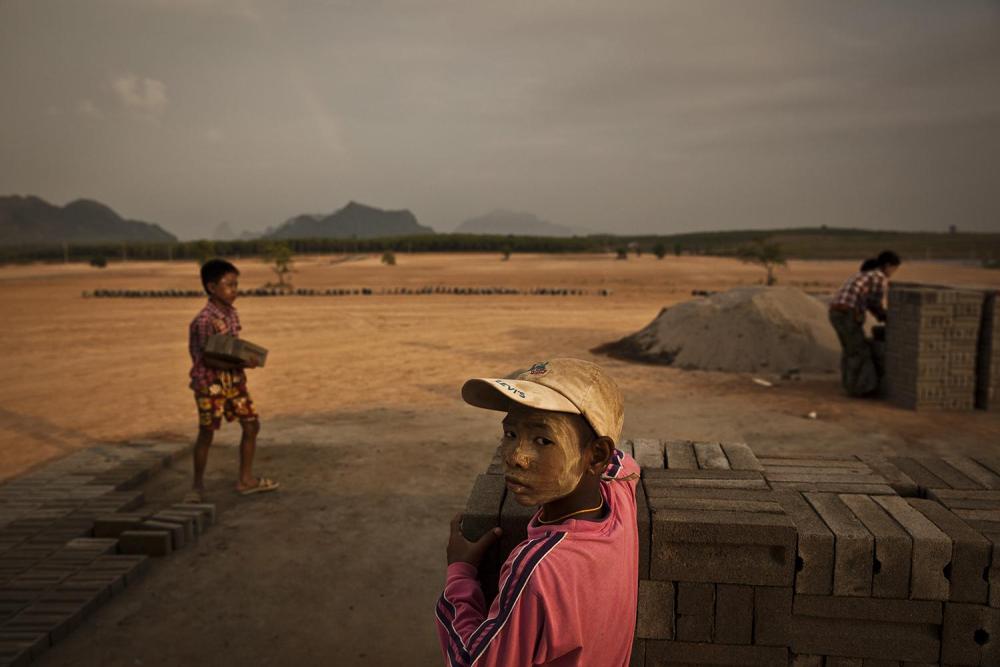 Children and adults making and stacking bricks on the construction site of the UMH Industrial Park special economic zone, north of the city of Hpa-an. Sand dug from the Salween River is used in the manufacture of the bricks. 