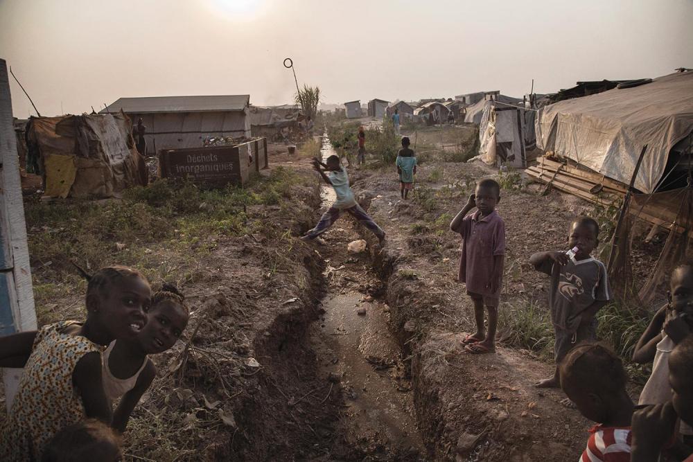 Des enfants dans le camp de personnes déplacées de Mpoko, à Bangui, en République centrafricaine. Le terrain rugueux de ce camp, parsemé de trous et de canalisations à ciel ouvert, y rend les déplacements de personnes handicapées extrêmement difficiles.