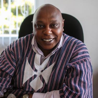 Photo of Maina Kiai, seated at a desk and smiling.
