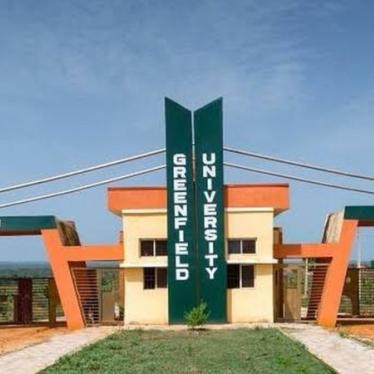 Photo shows Greenfield University in Nigeria, in the daylight with a green sign reading the university's name.