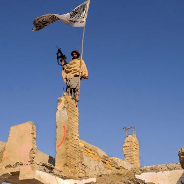A Taliban fighter raises a flag in the ruins of Sangin, Helmand province, Afghanistan, November 30, 2021.