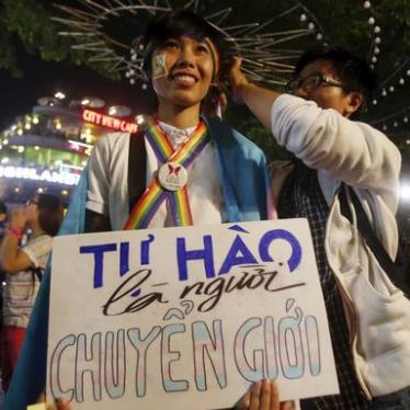 A participant holds a placard which reads "proud to be transgender" as they wait for an LGBT demonstration along a street in Hanoi.