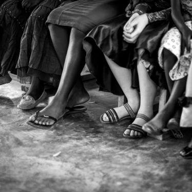 Children sitting in a row, among them one child with albinism. 