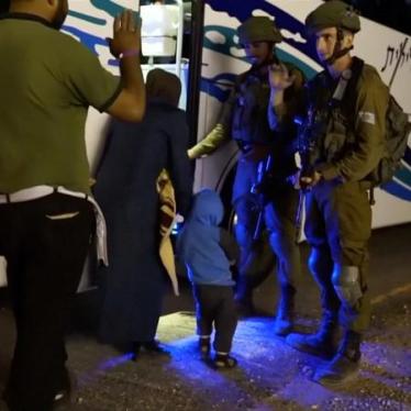 People walk past Israeli soldiers as they board a bus during the Syria Civil Defence, also known as the White Helmets, extraction from the Golan Heights in this still image taken from video, provided by the Israeli Army July 22, 2018.