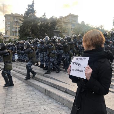 A protestor observes riot police during a peaceful protest in Central Moscow on August 10, 2019.